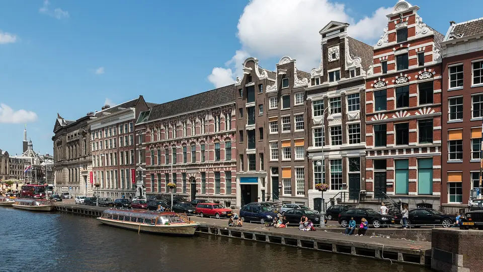 Gabled canal houses along the Rokin waterfront in Amsterdam under a blue summer sky