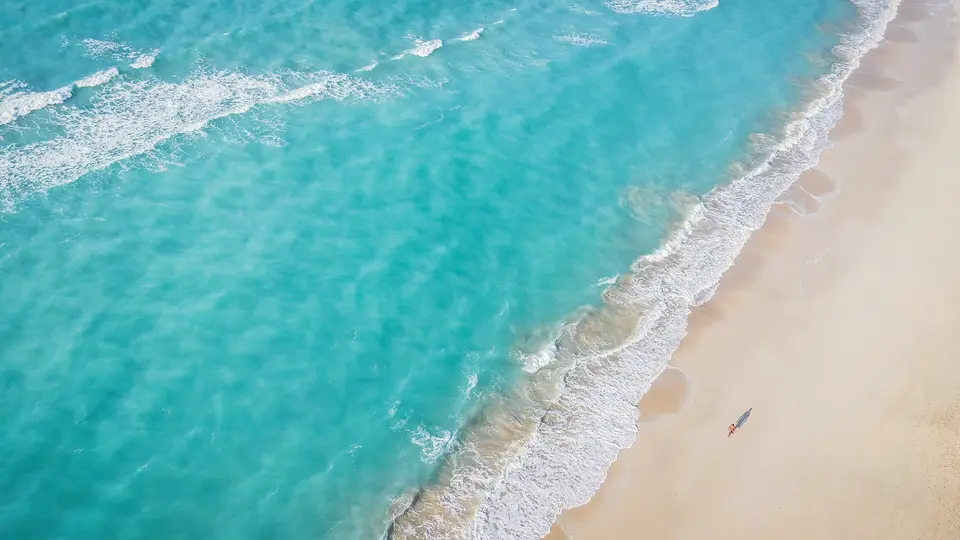 Turquoise shallows breaking on the white sand beach of Saadiyat Island, seen from above