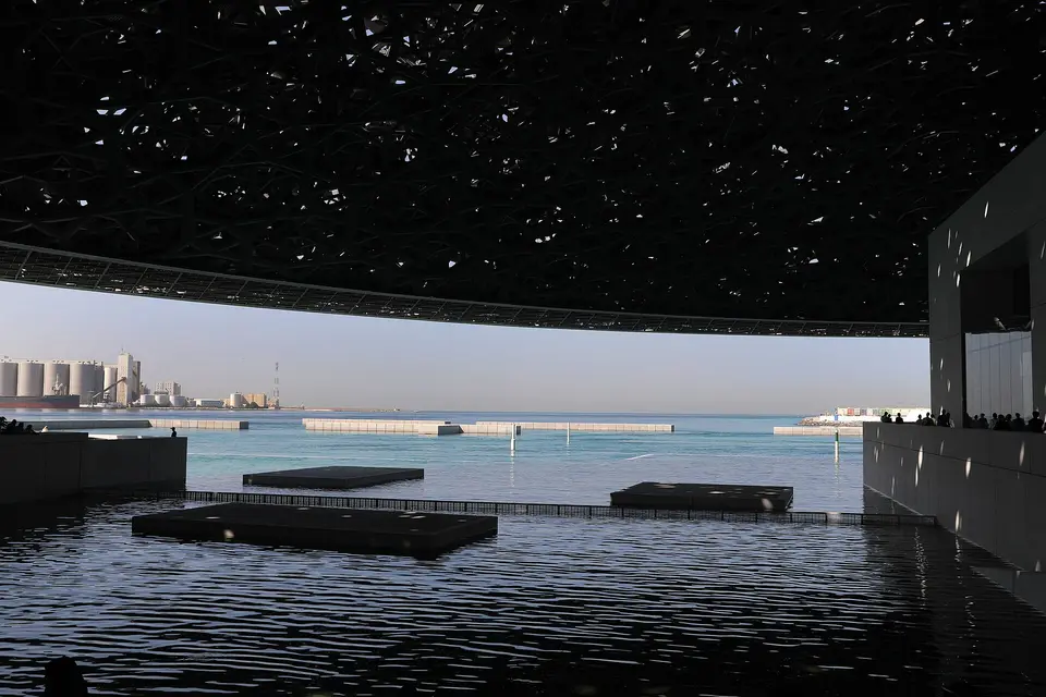 The sea and a distant port framed by the latticed dome of the Louvre Abu Dhabi