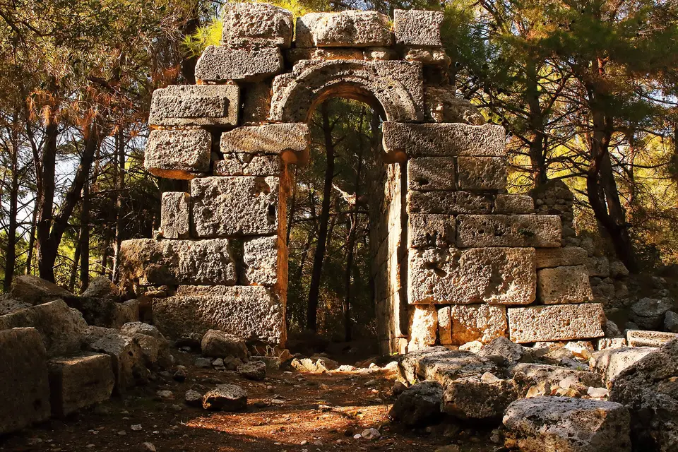 A stone arched gateway among pine trees in the ruins of ancient Phaselis