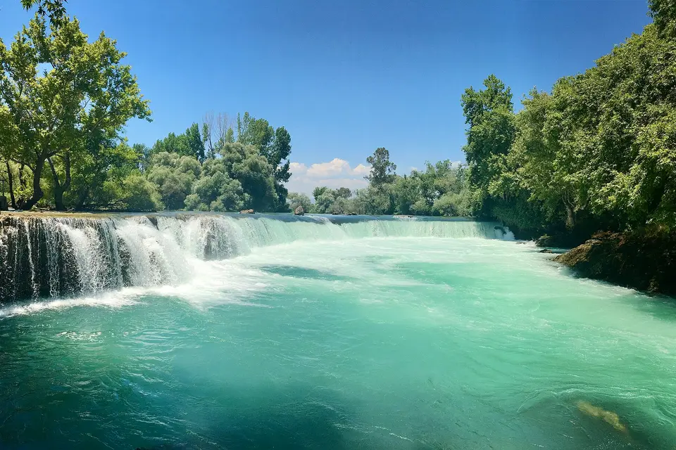 Manavgat Waterfall spilling into a turquoise river between trees near Side