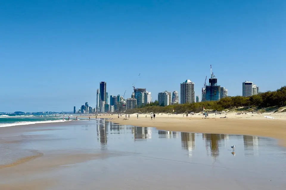 Gold Coast high-rises reflected in the wet sand of Main Beach under a clear sky
