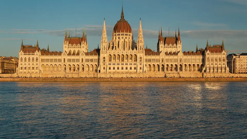 The Hungarian Parliament Building in Budapest lit by low sun across the Danube