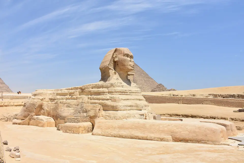 The Great Sphinx resting before the Pyramid of Khafre under a blue sky at Giza