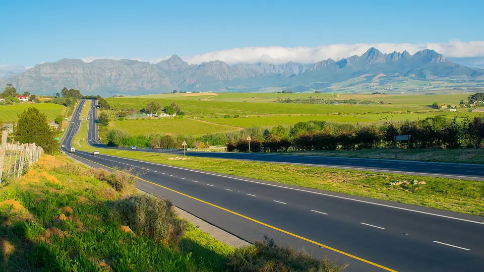 The road from Cape Town towards Stellenbosch through vineyards below jagged mountains