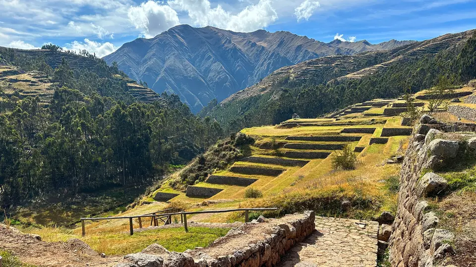 Stepped Inca farming terraces at Chinchero below forested slopes and high Andean peaks