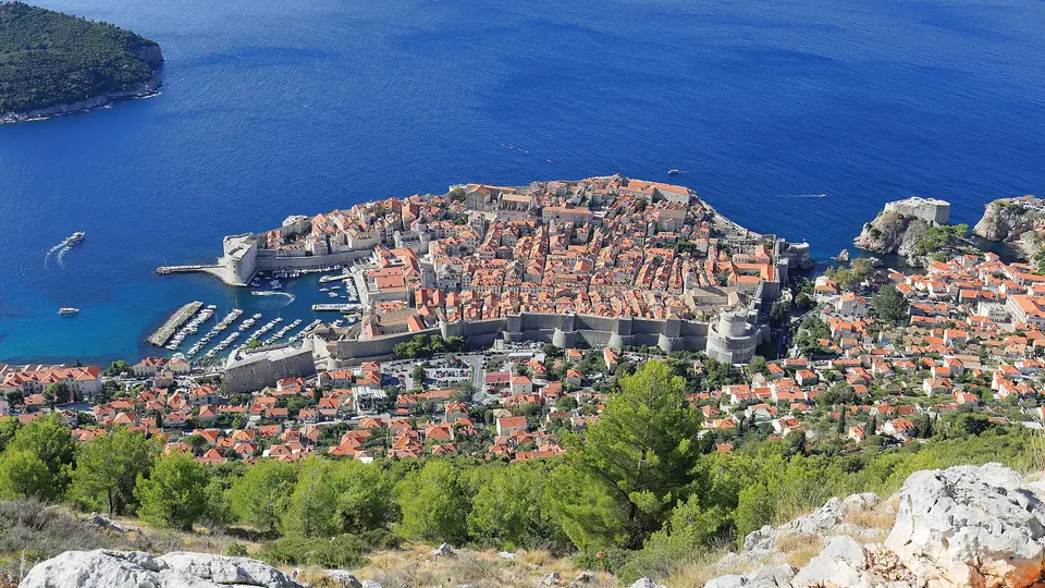 Dubrovnik Old Town with its walls, harbour and red roofs, seen from Mount Srđ above the sea