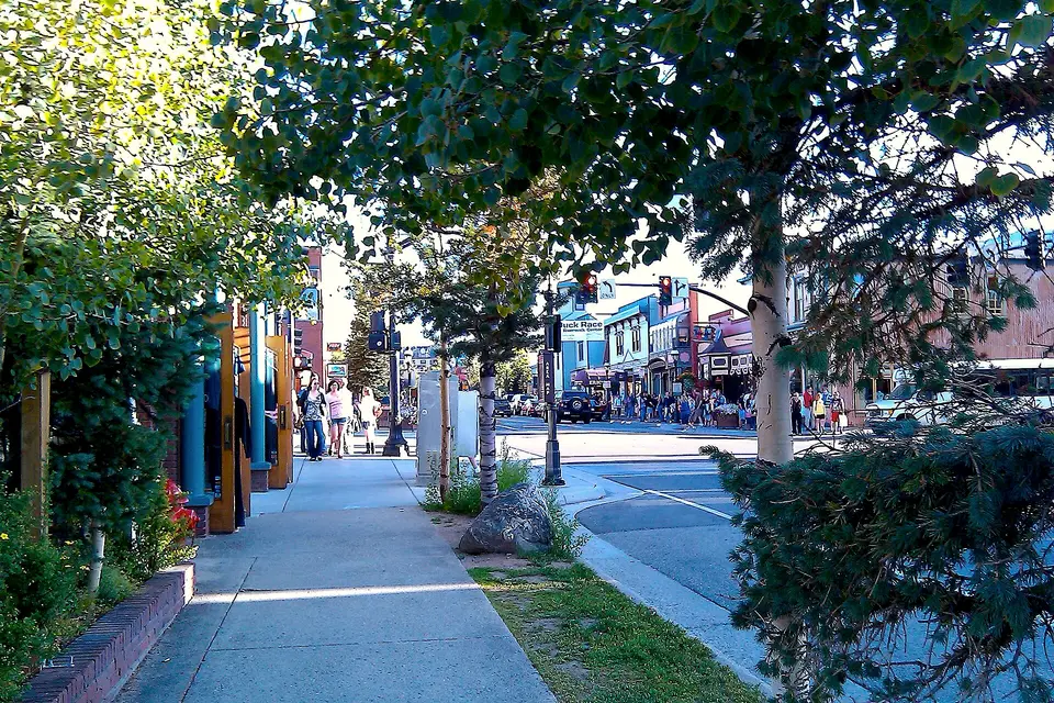 Tree-lined sidewalk and colourful shopfronts along Main Street in Breckenridge on a sunny day