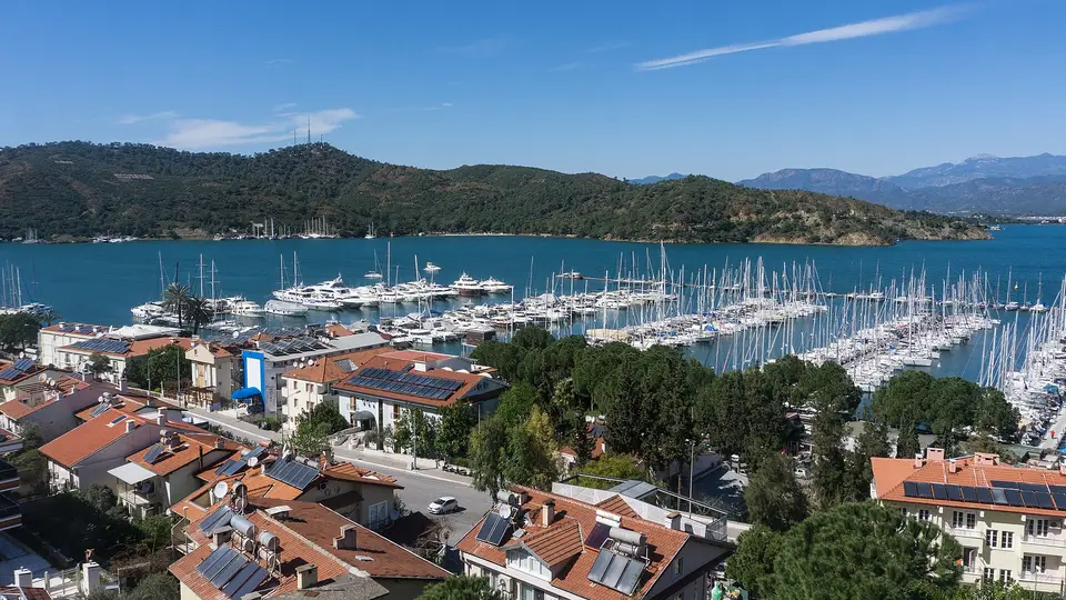Red-roofed houses above the marina and yacht moorings of Fethiye Bay on a clear day