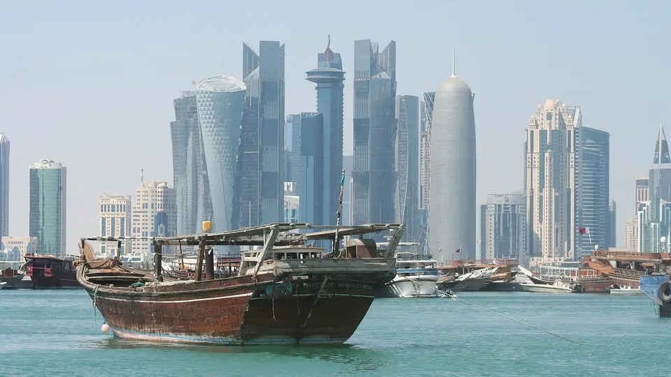 A wooden dhow on the water of Doha Bay in front of the West Bay towers