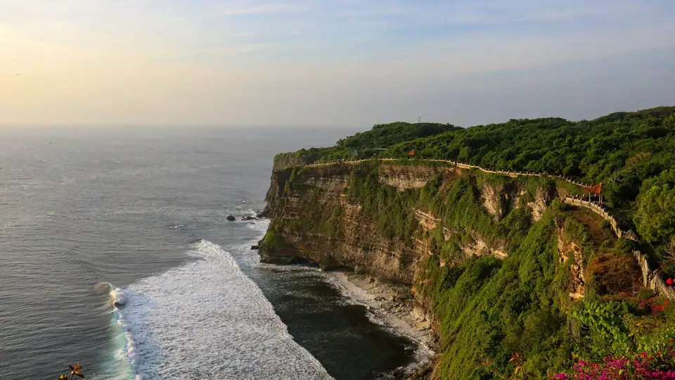 Green cliffs and breaking surf below Uluwatu Temple on Bali's southern coast in evening light