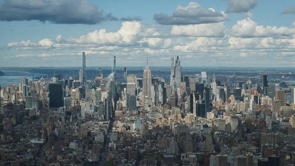 Midtown Manhattan and the Empire State Building seen from high above, under scattered clouds