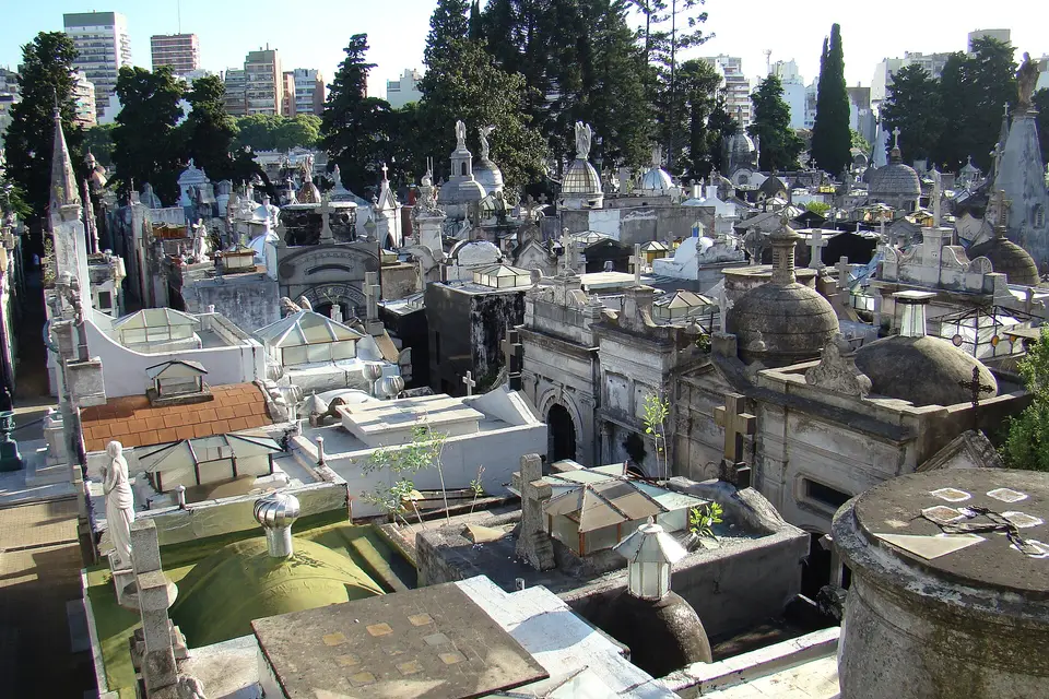 Domed mausoleums and statues of Recoleta Cemetery in Buenos Aires among trees and apartment blocks