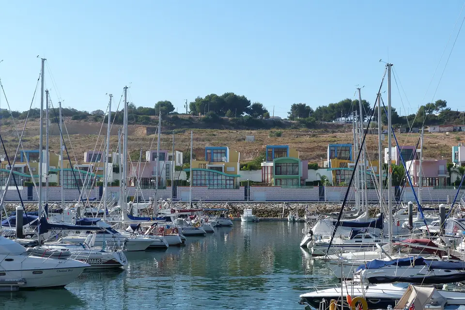 Sailing boats moored in Albufeira Marina in front of brightly painted houses