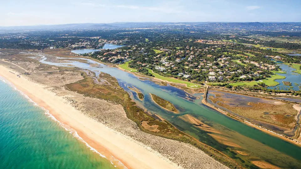 Aerial view of Quinta do Lago with its beach, the Ria Formosa lagoon and villas among pine woods
