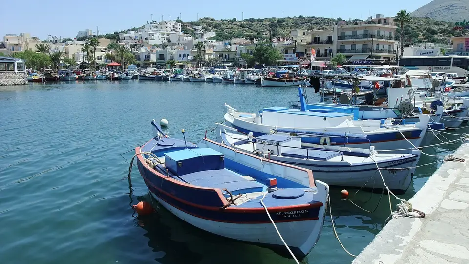 Fishing boats moored in Elounda harbour with the waterfront town and hills behind