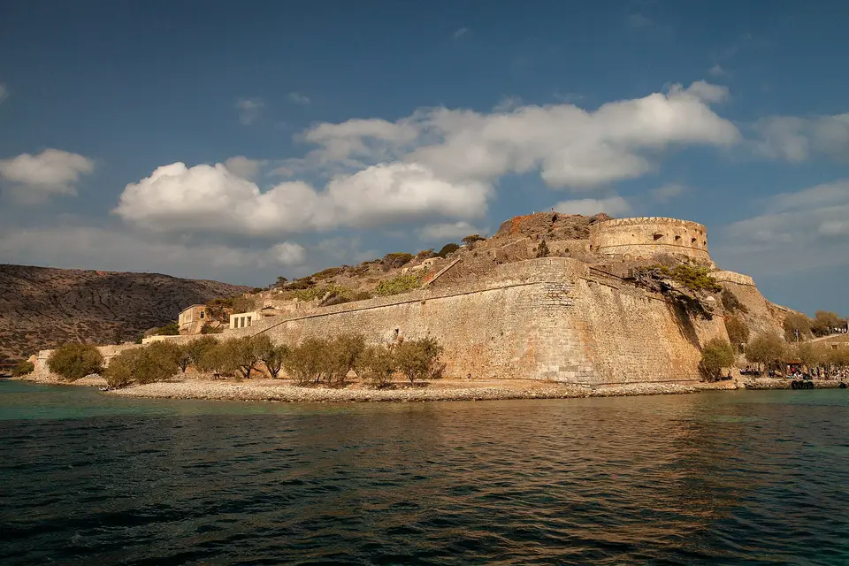 The Venetian fortress on Spinalonga island rising above the calm water of the bay