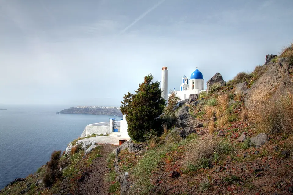 The blue-domed Panagia Theoskepasti church on a rocky slope above the caldera at Imerovigli