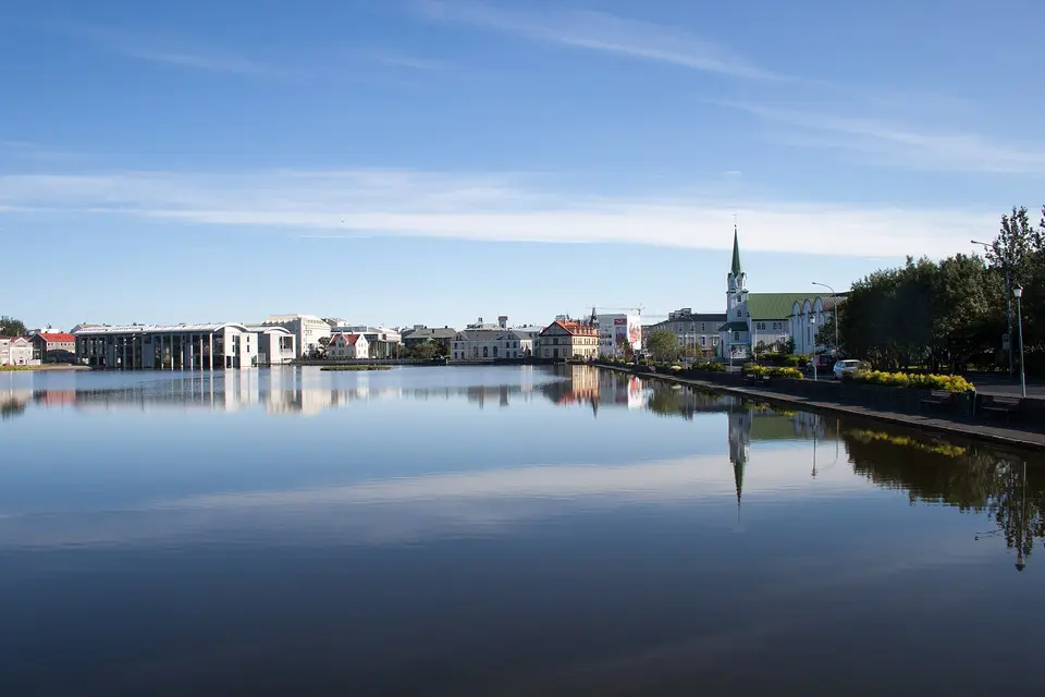 Still water of Tjörnin lake reflecting Reykjavík's Fríkirkjan church and lakeside buildings