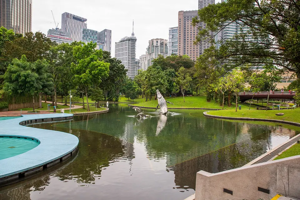 Lawns, tropical trees and a curving pool in KLCC Park below surrounding office towers