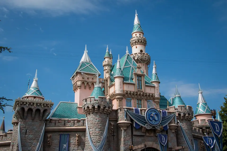 The pink and turquoise turrets of Sleeping Beauty Castle at Disneyland against a blue sky