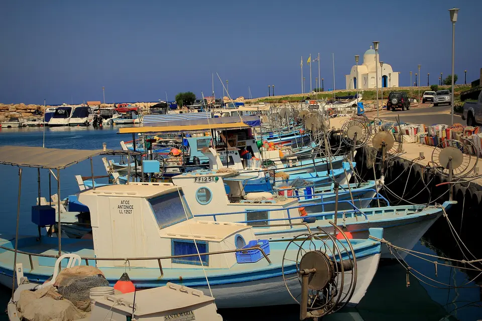 Fishing boats moored in Ayia Napa harbour with a small white chapel on the quay