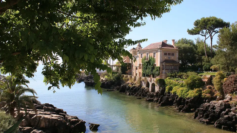 The Casa de Santa Maria mansion above a small rocky inlet of clear water in Cascais