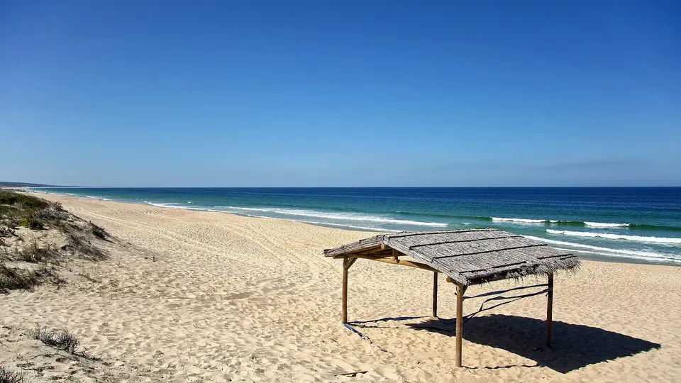 Empty sand and a wooden beach shelter on the coast between Carvalhal and Pego near Comporta