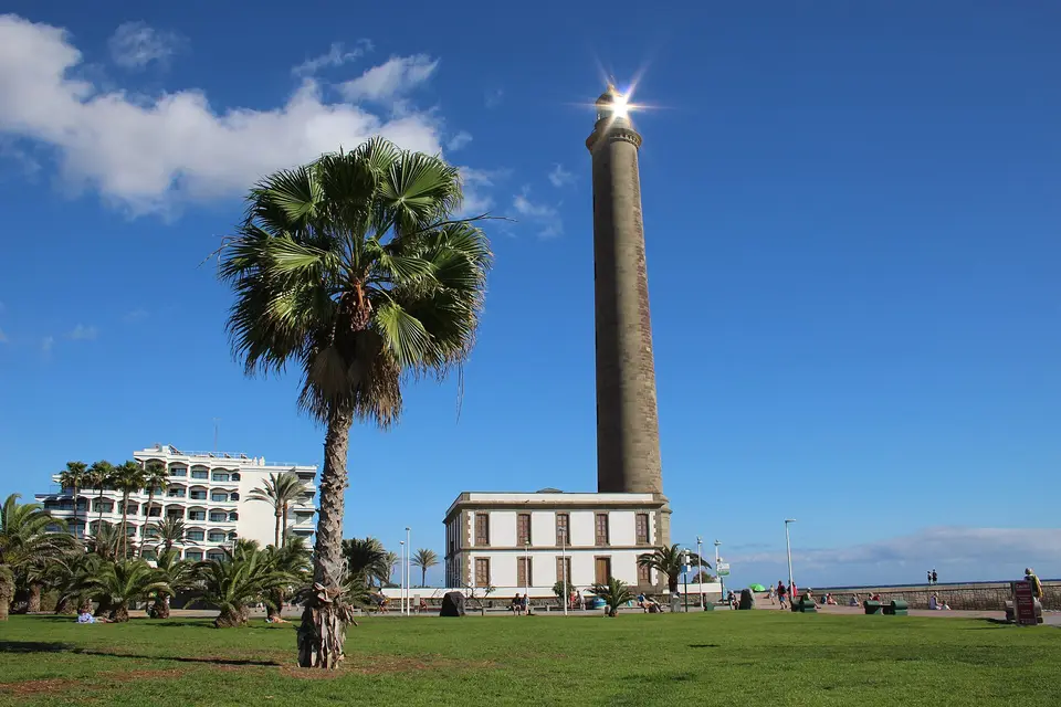 The Faro de Maspalomas lighthouse rising behind palms and lawn on a sunny day