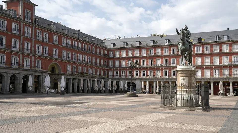 The quiet Plaza Mayor in Madrid with its red arcaded buildings and equestrian statue