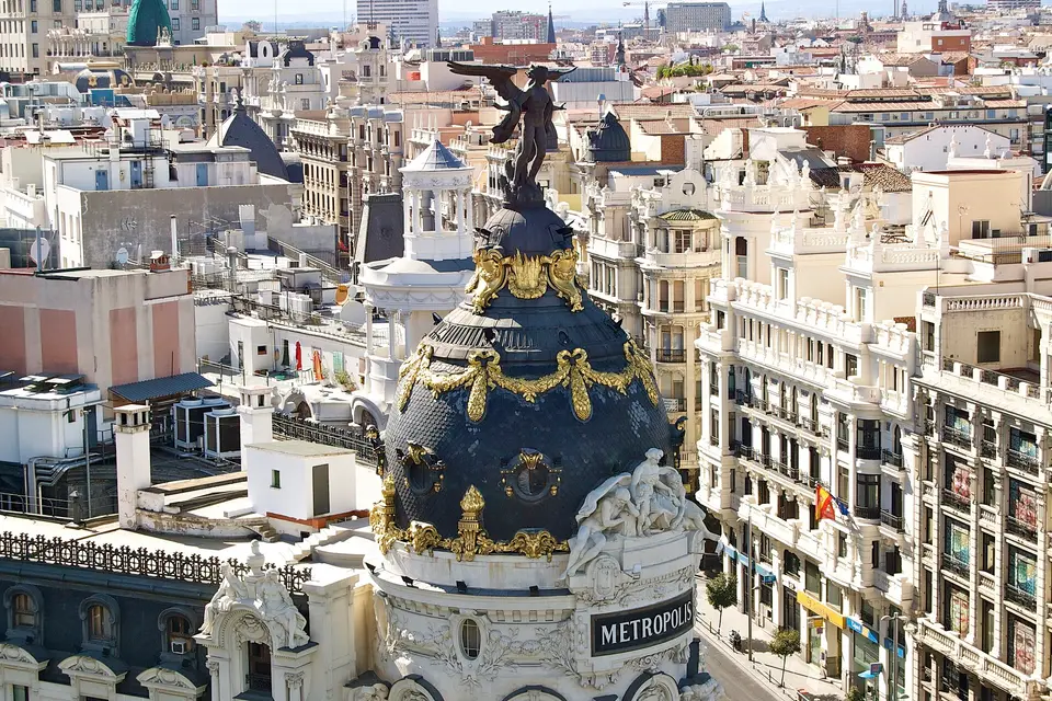 The gilded dome and winged statue of the Metrópolis Building above the rooftops of central Madrid