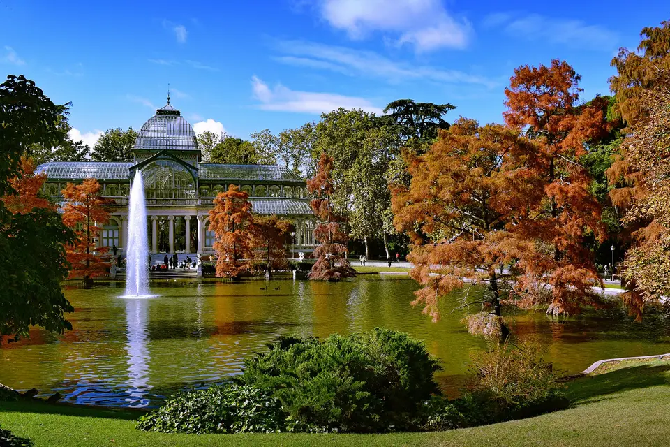 The Crystal Palace, its fountain and autumn trees reflected in the pond in Madrid's Retiro Park