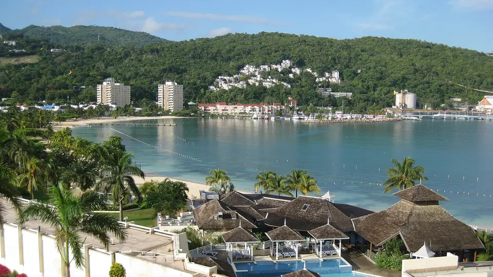 The curving beach, calm bay and wooded hills of the town of Ocho Rios, Jamaica