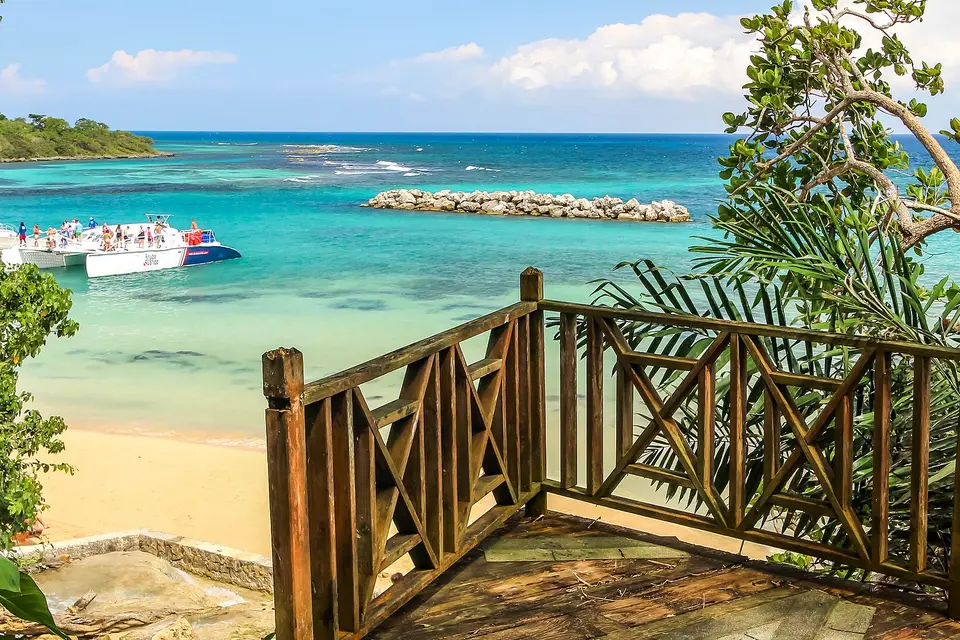 Turquoise water and a sandy cove below a wooden lookout at Dunn's River Falls beach, Ocho Rios