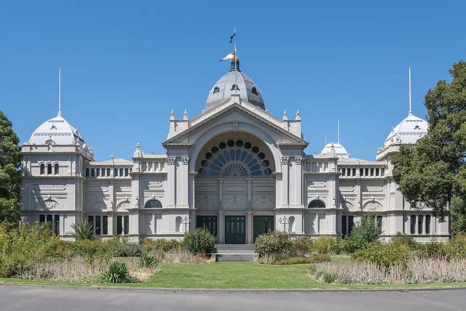 The domed Royal Exhibition Building in Melbourne behind flower beds and a lawn in Carlton Gardens