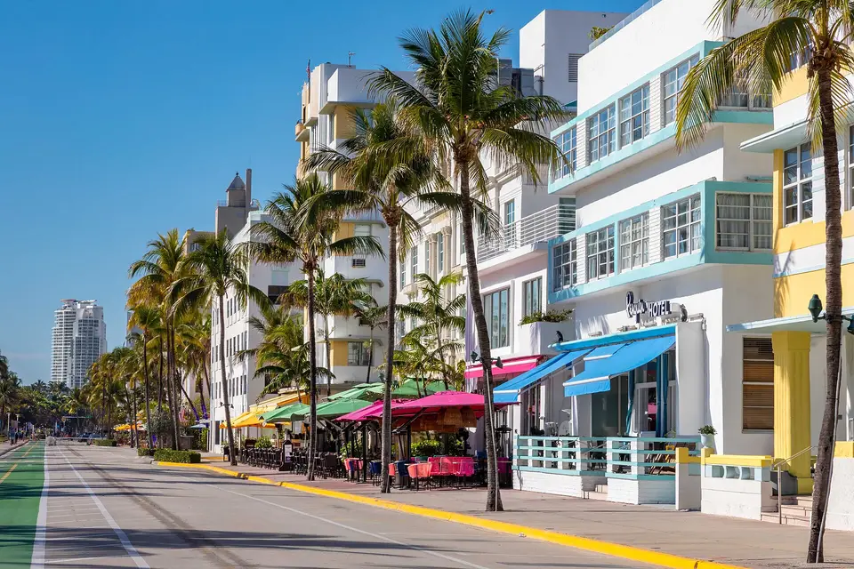 Pastel Art Deco hotels and palm trees lining an empty Ocean Drive in Miami Beach
