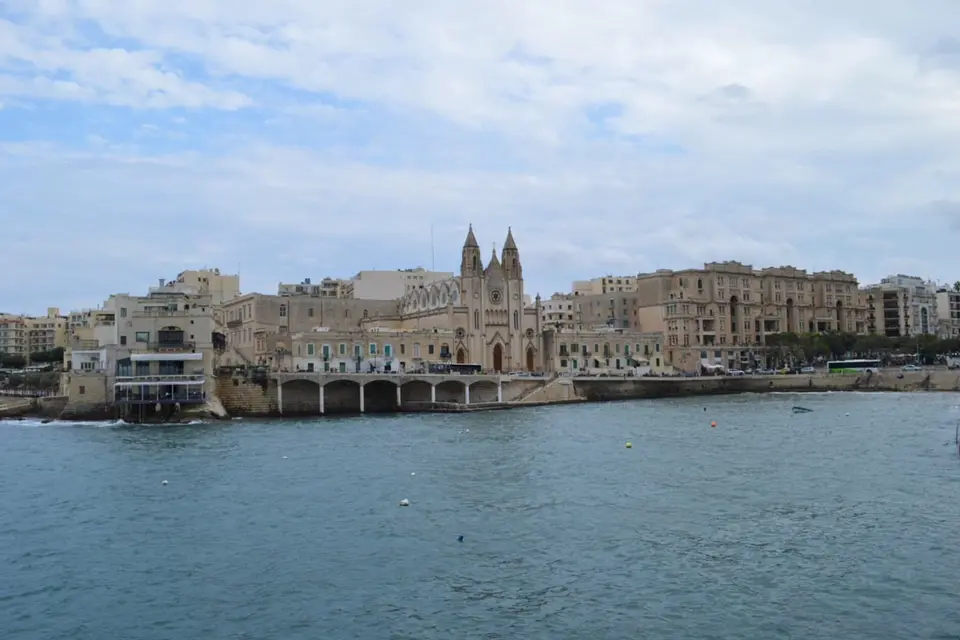 The neo-Gothic Carmelite church and old seafront buildings across the water at Balluta Bay