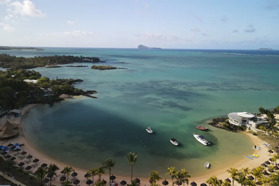 Aerial view of a palm-lined bay at Grand Gaube, with Coin de Mire island offshore