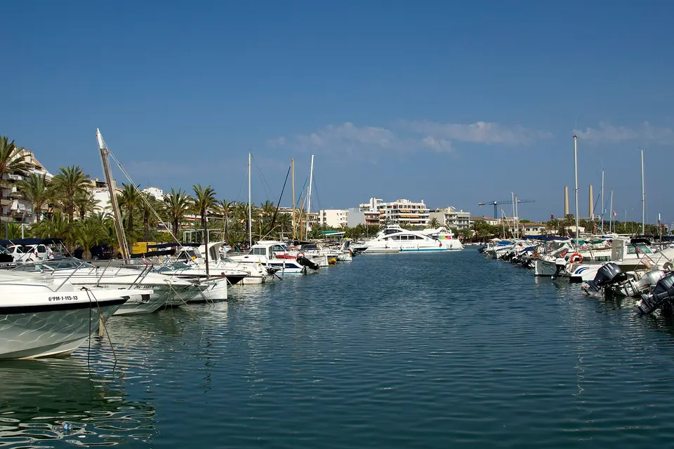 Motorboats and yachts moored along the palm-lined marina at Port d'Alcúdia