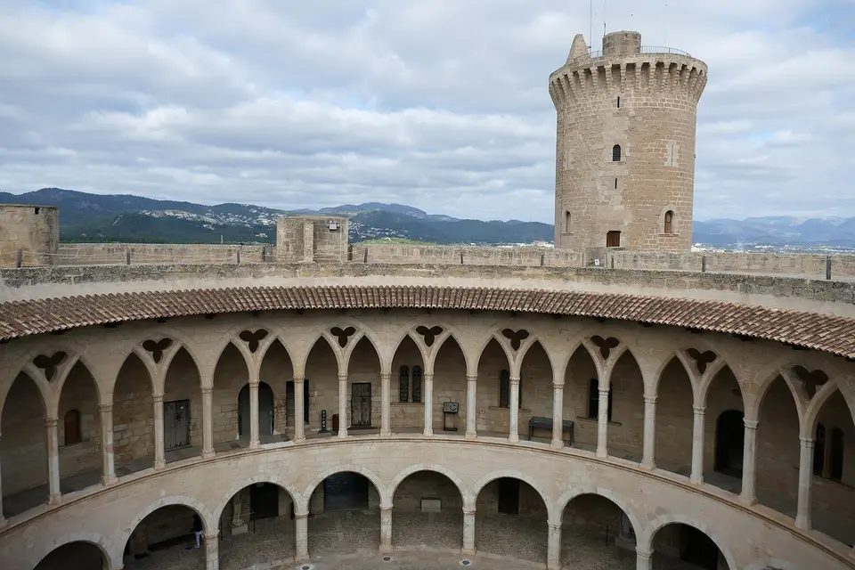 The round arcaded courtyard and stone keep of Bellver Castle above Palma, with hills behind