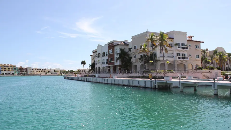 Palm-lined waterfront buildings beside the turquoise water of the Cap Cana marina