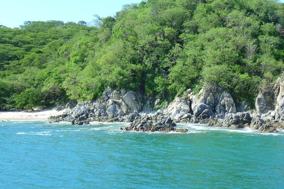 Wooded hills and rocks around the turquoise cove of Playa Palito Verde near La Cruz de Huanacaxtle
