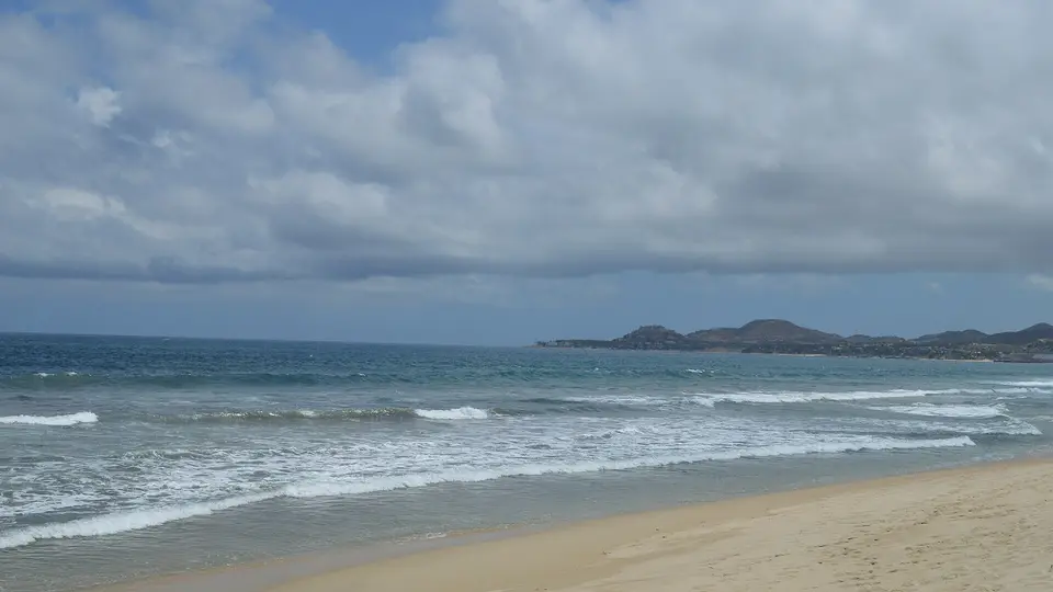 Waves breaking on the wide sandy beach of San José del Cabo with rocky headlands beyond