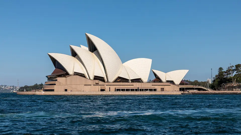 The Sydney Opera House on Bennelong Point seen across the blue water of Sydney Harbour