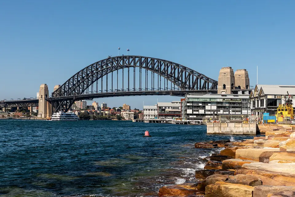 The steel arch of the Sydney Harbour Bridge above the harbour and the Walsh Bay waterfront
