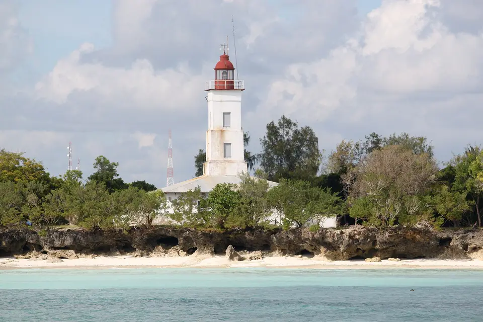 The white lighthouse at Ras Nungwi standing above coral rock and pale green water