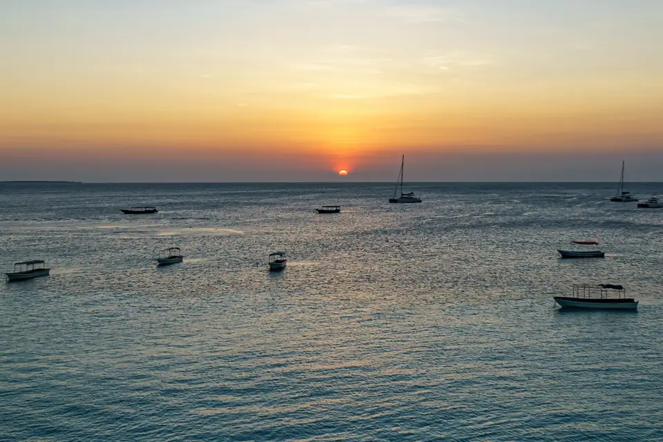 The sun setting over the sea off Nungwi with small boats and yachts at anchor