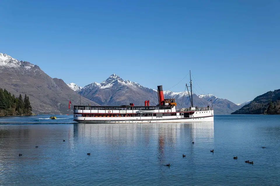 The red-funnelled TSS Earnslaw steamship on calm Lake Wakatipu below snow-capped peaks near Queenstown