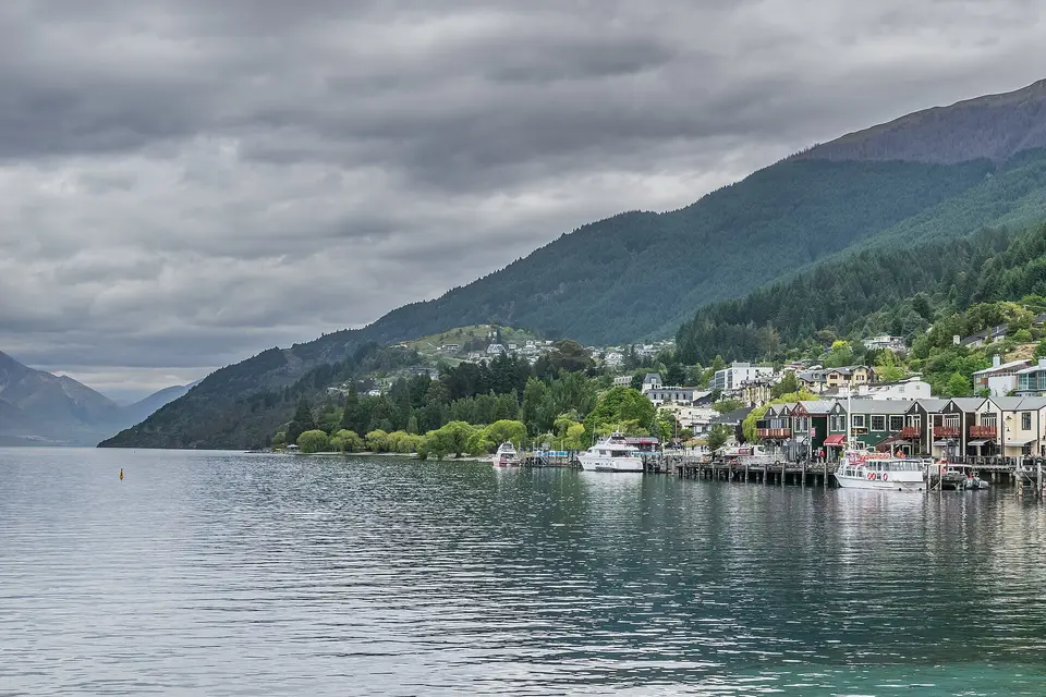 Queenstown's lakefront wharves and hillside houses on Lake Wakatipu beneath a cloudy sky